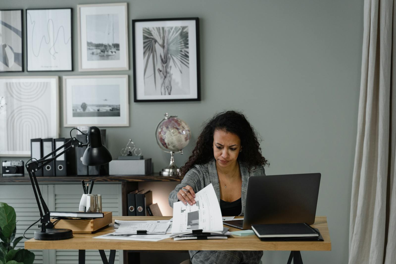 Focused professional adult reviewing documents at desk in a modern office setting. Administrator